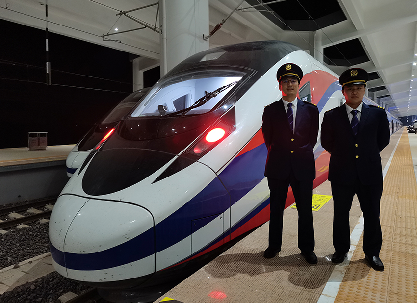 劉銀能（右一）與中國(guó)師父鄔俊鴻在動(dòng)車組前合影。受訪者供圖